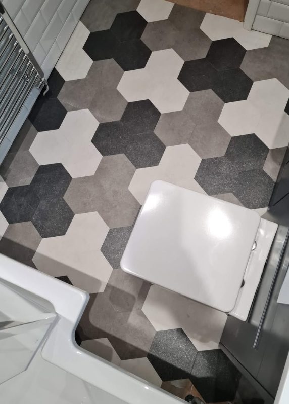 Grey, white and black hexagonal-pattern bathroom flooring around fixtures