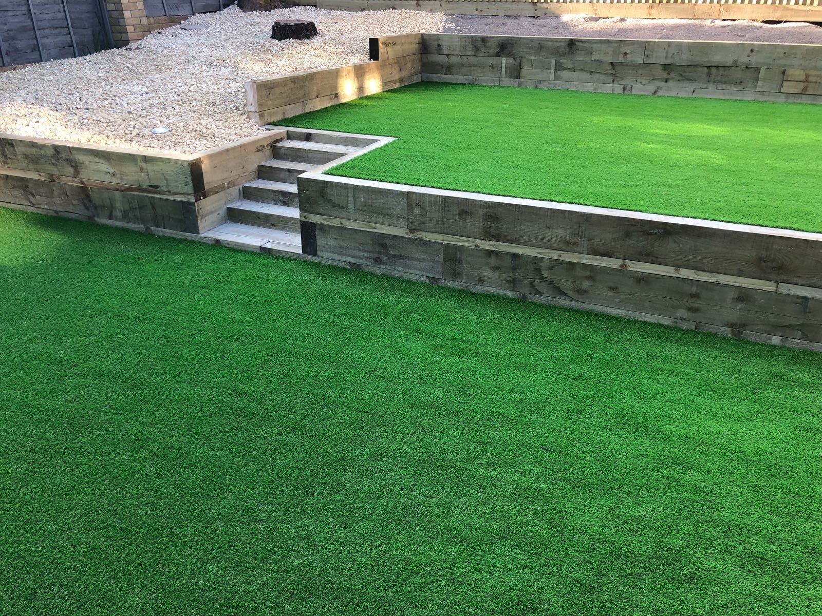 Artificial grass on two garden levels separated by timber walls and steps