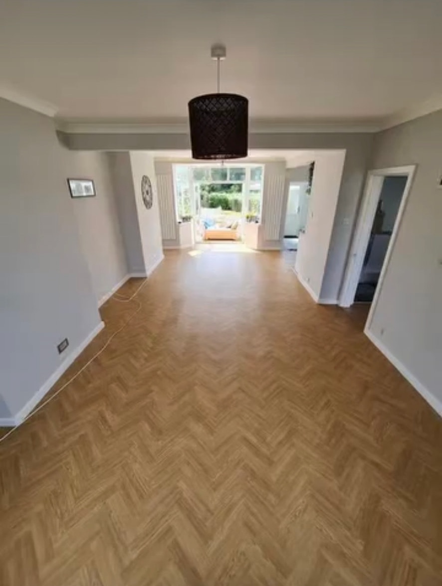 Natural-tone herringbone flooring through a bright living room