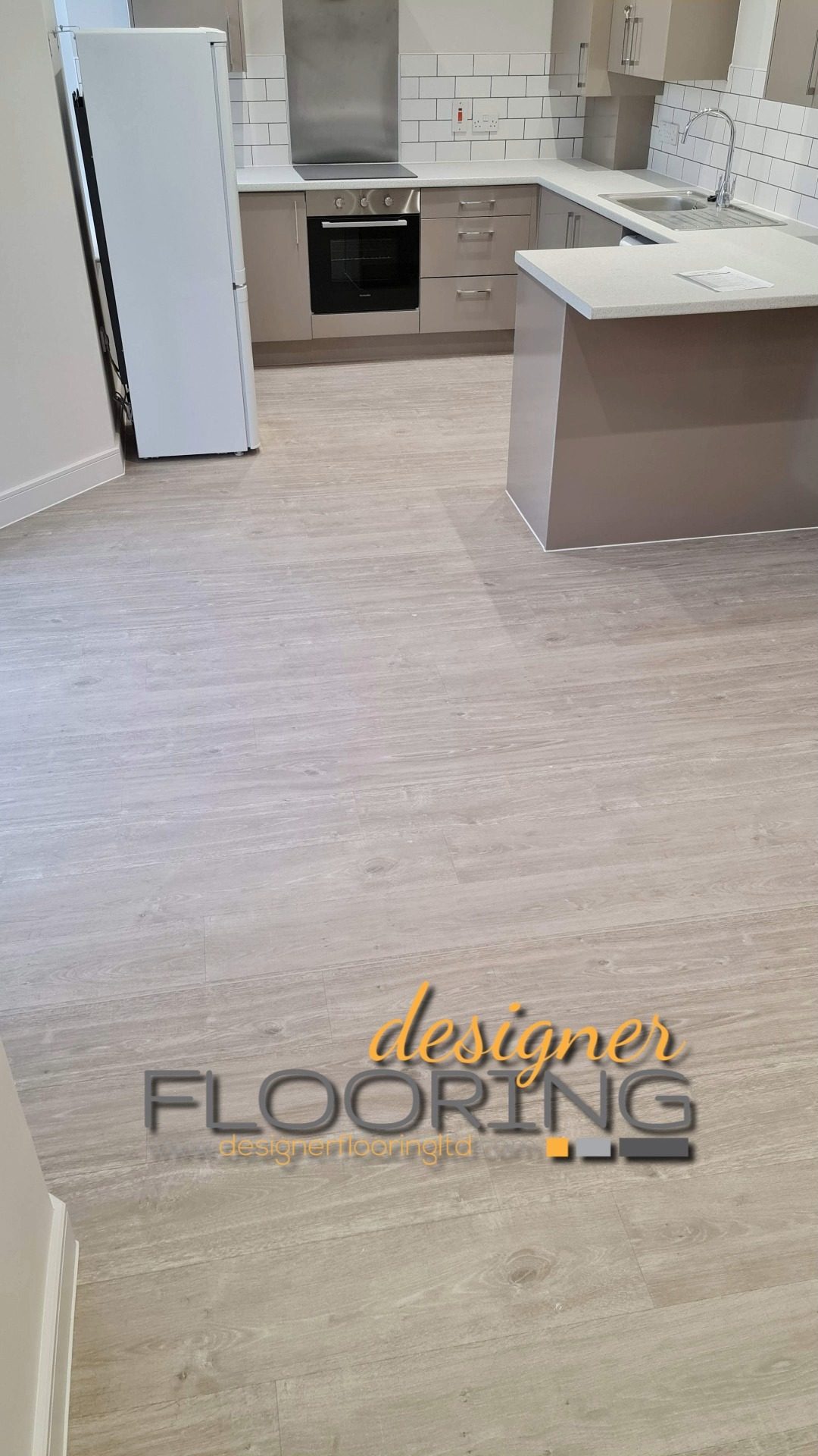 Pale wood-effect plank flooring fitted around a kitchen island