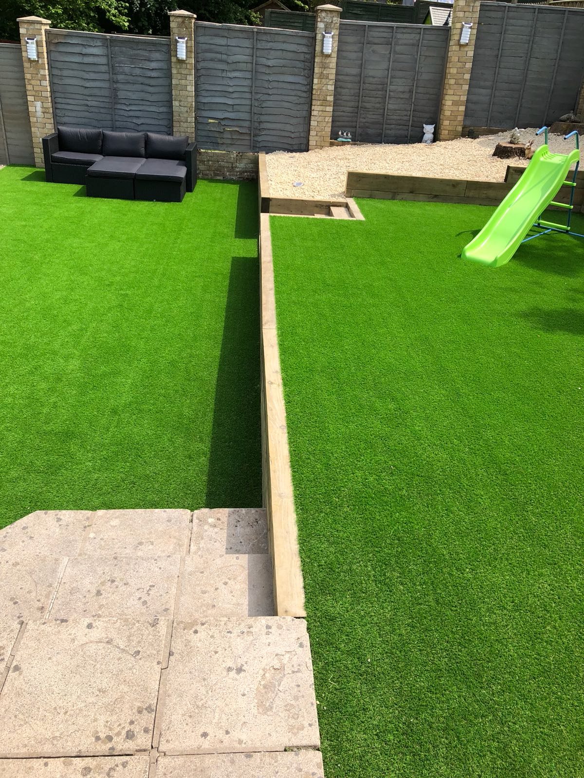 Artificial grass lawn with a paved step, seating and children’s slide