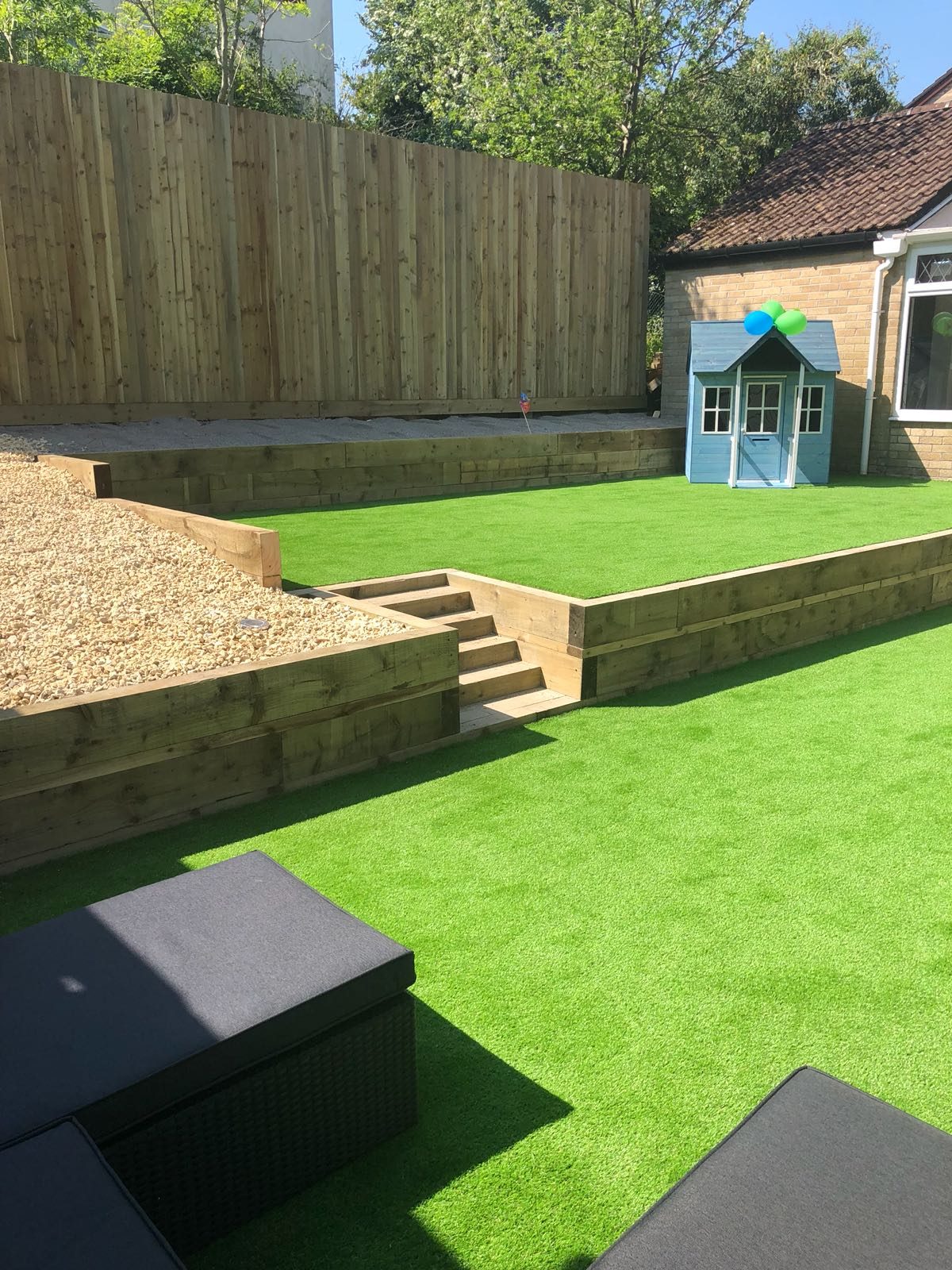 Two-level artificial grass garden with timber retaining walls and steps