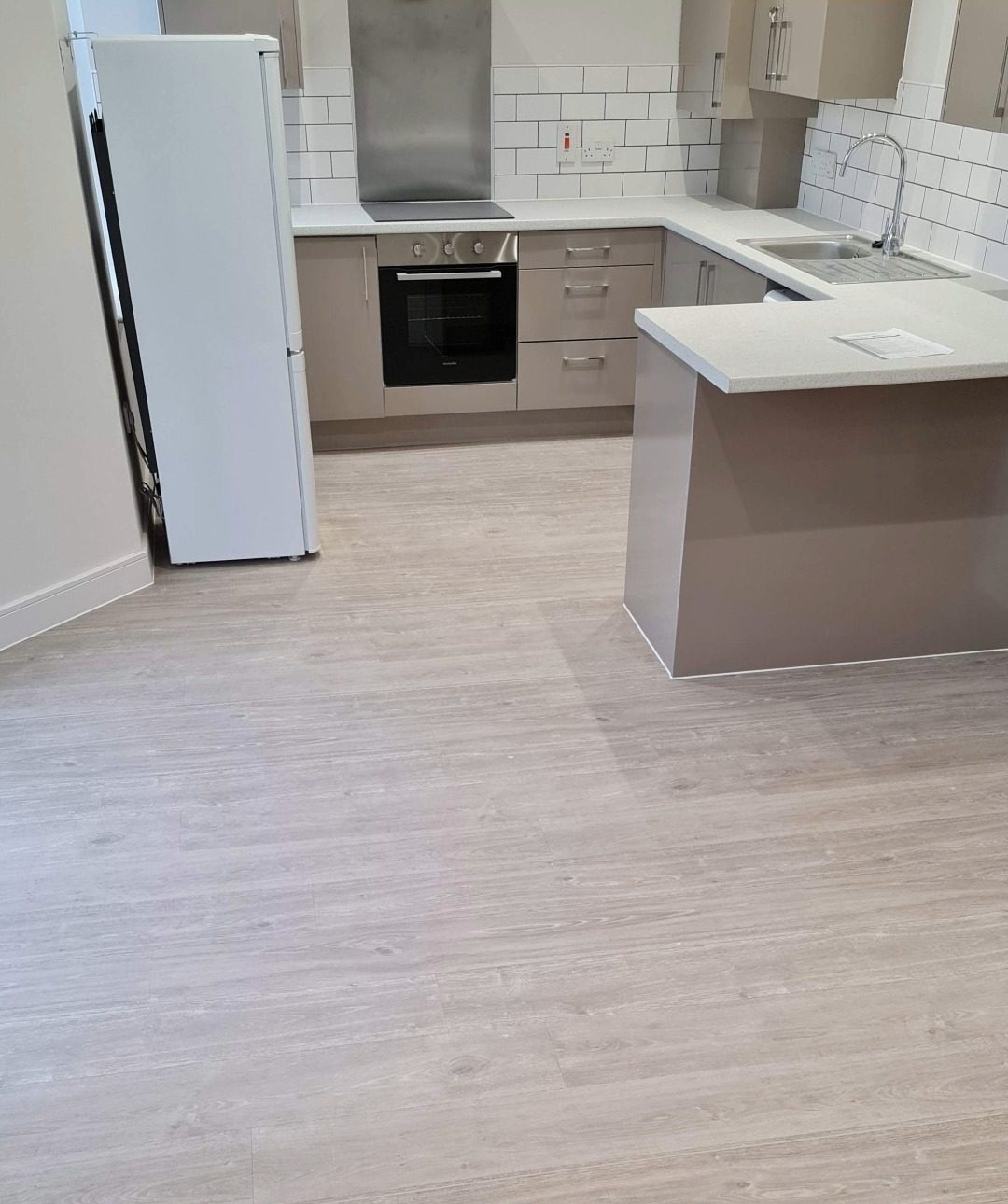 Pale wood-effect LVT flooring through a kitchen