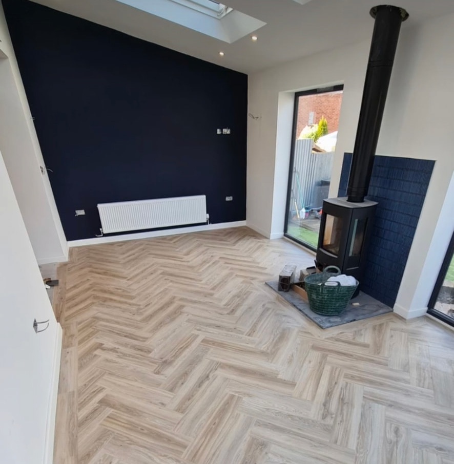 Pale herringbone flooring beside a wood-burning stove
