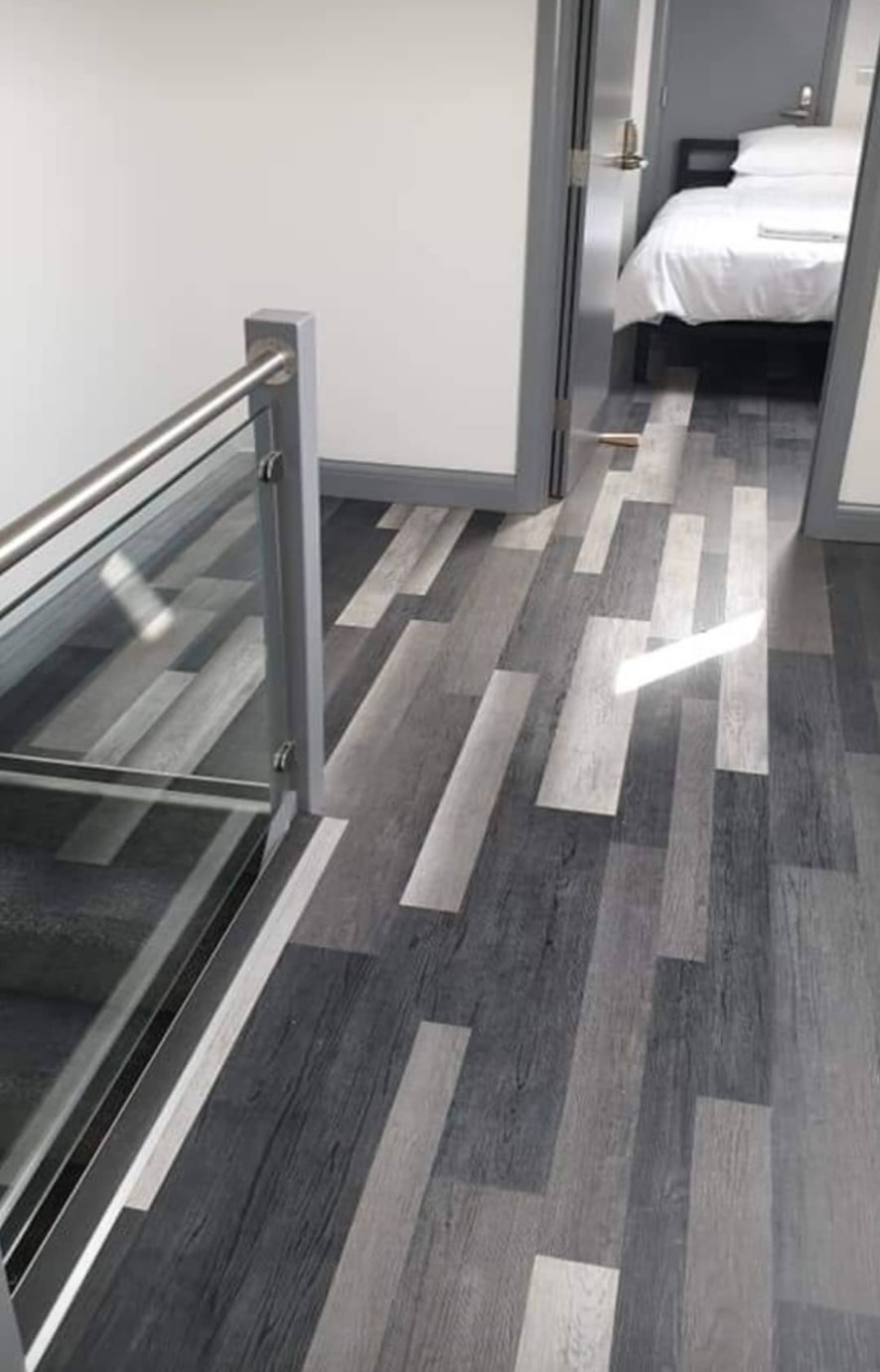 Contrasting grey plank-pattern flooring across a landing and bedroom doorway