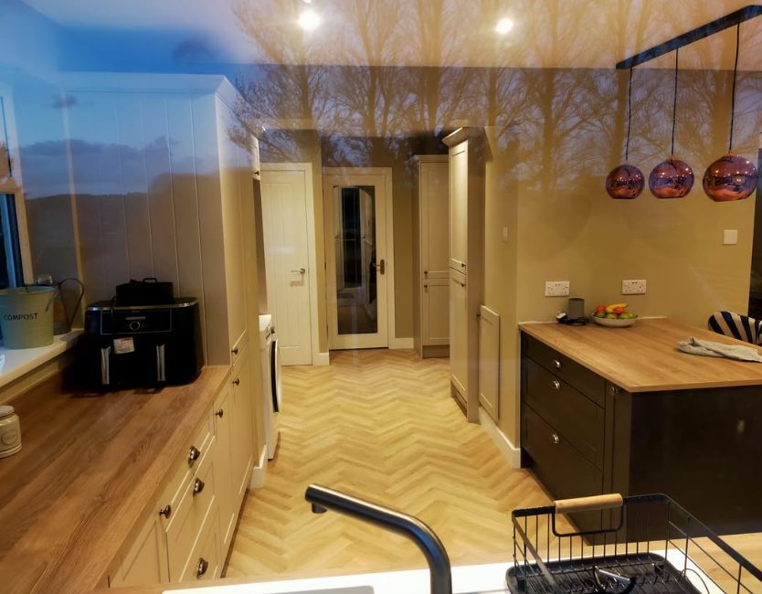 Natural-tone herringbone kitchen flooring beside fitted cabinets