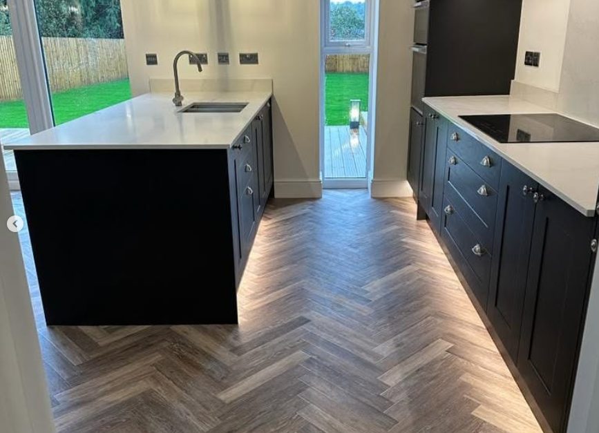 Herringbone-pattern kitchen floor between cabinets and glazed garden doors