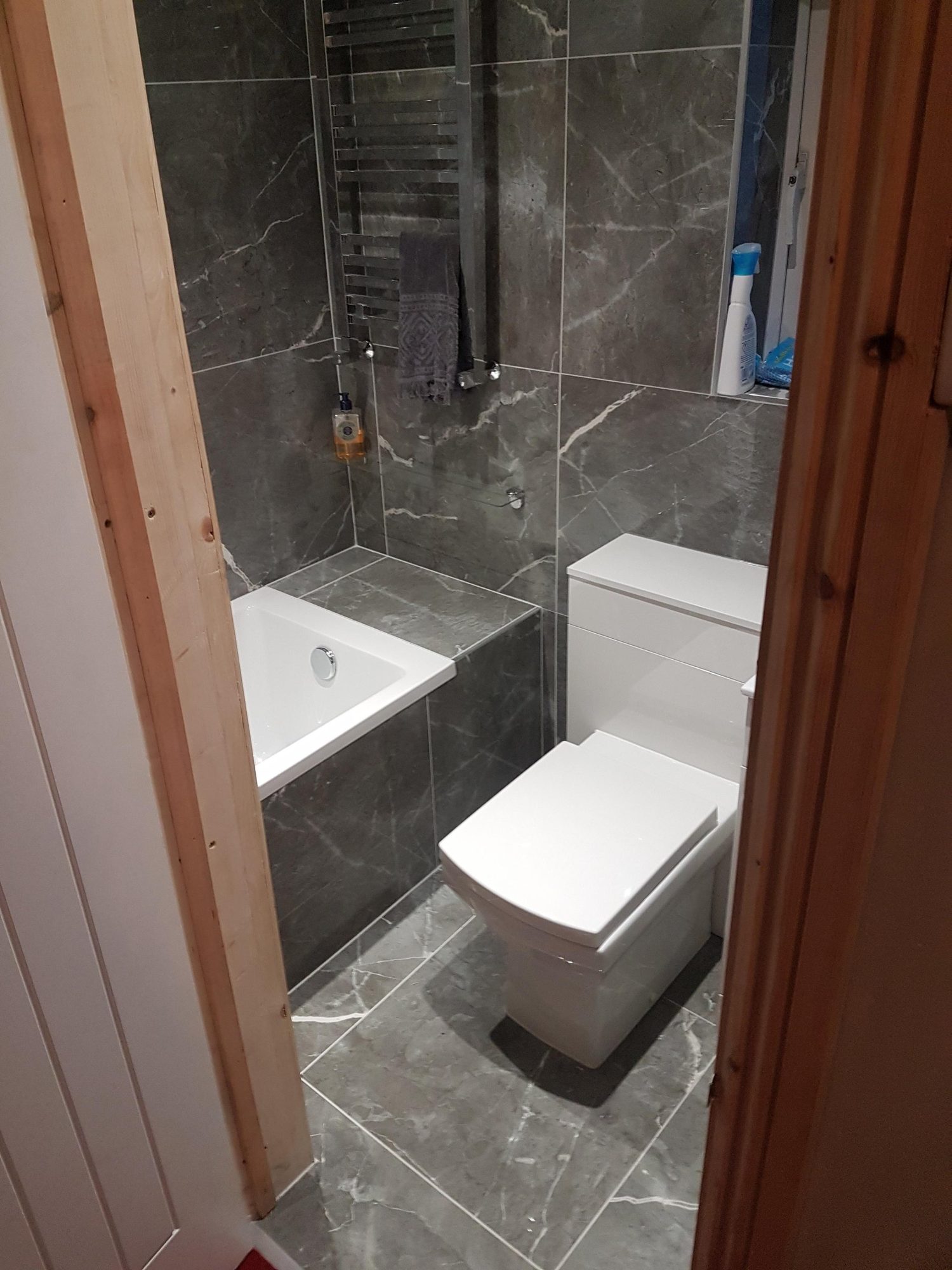 Dark stone-effect bathroom flooring around a toilet and shower