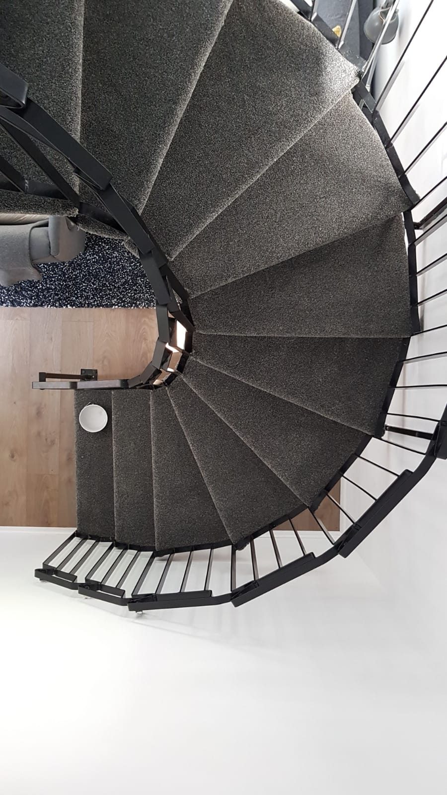 Dark carpet fitted to the curved treads of a spiral staircase