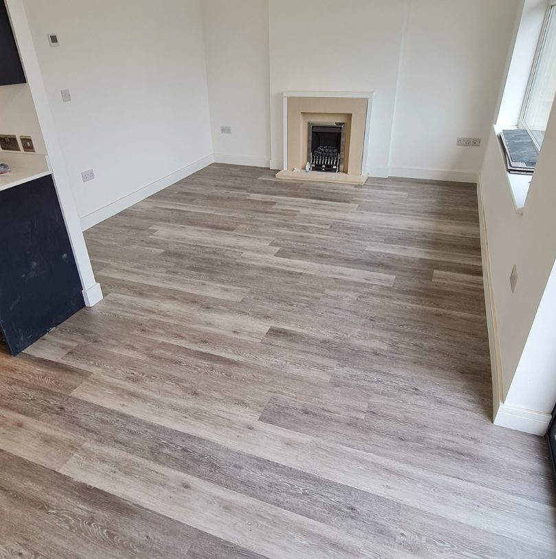 Grey wood-effect flooring in a living room beside a fireplace