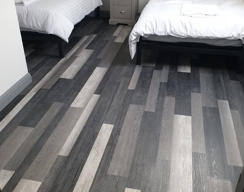 Grey plank-pattern floor fitted around twin beds