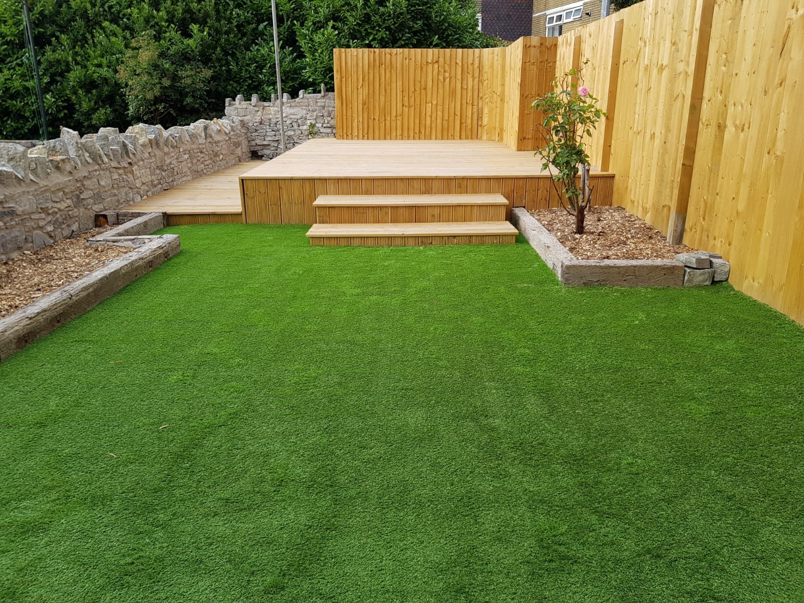 Artificial grass garden with timber decking and central steps