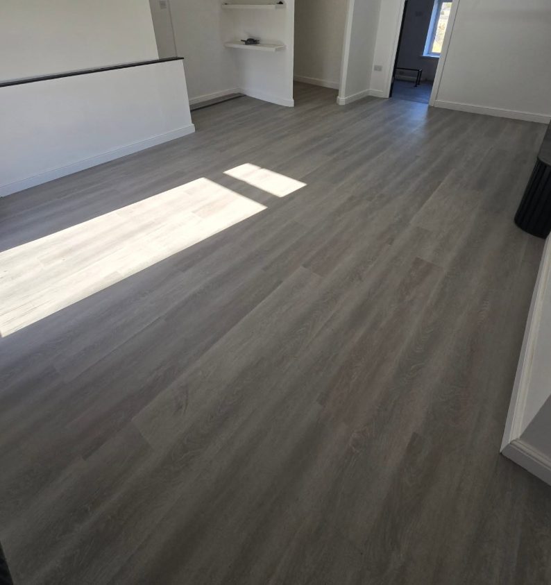 Grey wood-effect plank flooring beside a kitchen opening