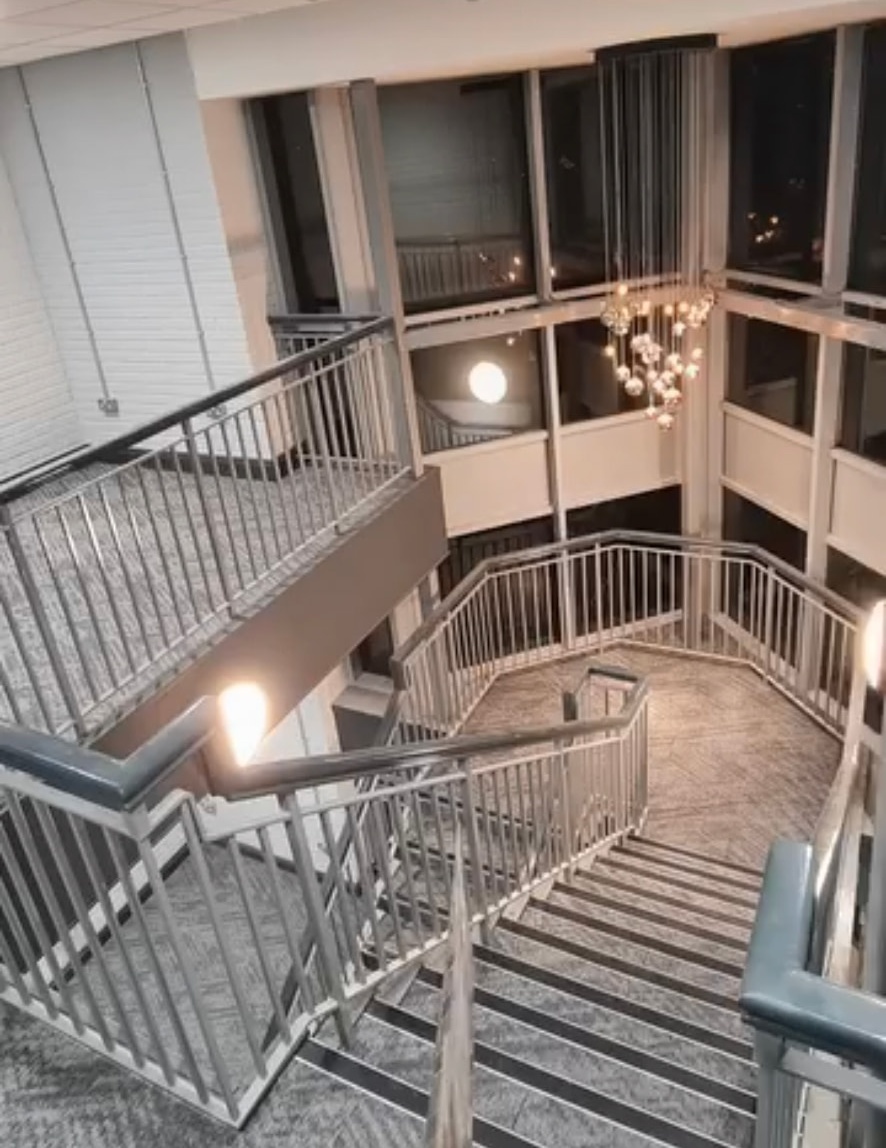 Grey carpeted commercial staircase and landings with metal balustrades