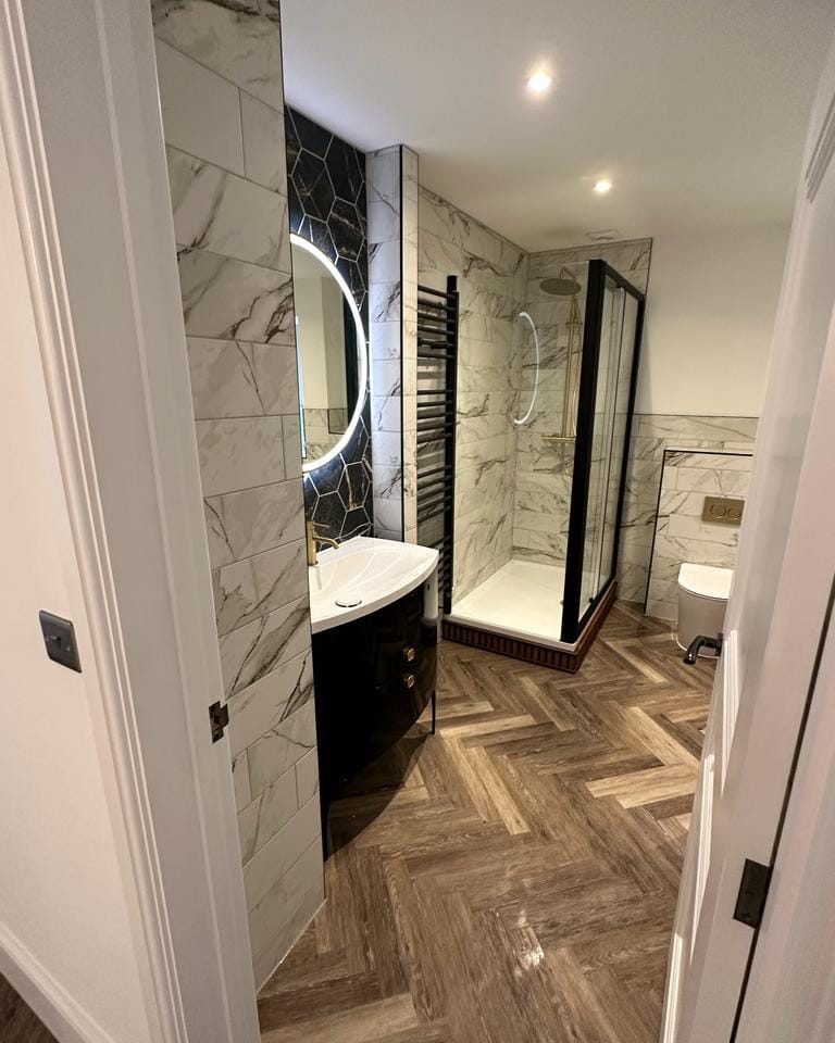 Wood-effect herringbone bathroom flooring fitted around a vanity and shower