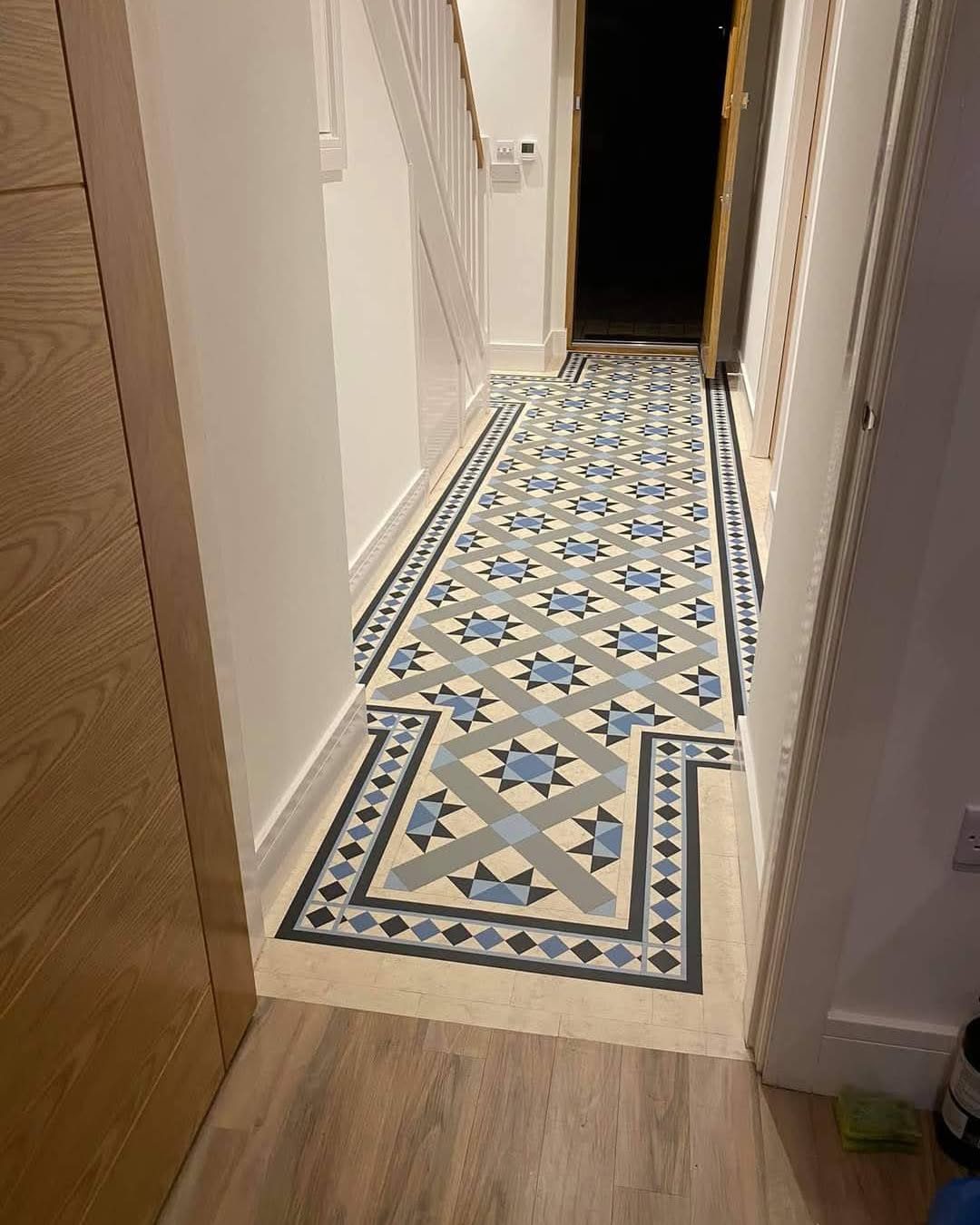 Geometric hallway flooring with decorative borders beside wood-effect planks