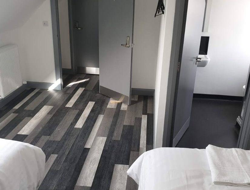Grey plank-pattern flooring fitted through a bedroom doorway